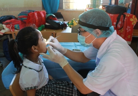 Bác sĩ của phòng khám bác sĩ Cường khám răng cho học sinh Trường tiểu học Hoàng Hoa Thám.