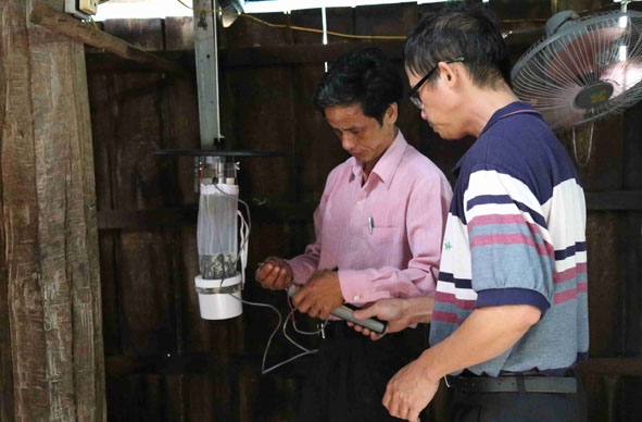 Cán bộ y tế lắp đặt thiết bị bắt muỗi để lấy mẫu phân tích tại một hộ gia đình  ở xã Krông Na, huyện Buôn Đôn. 