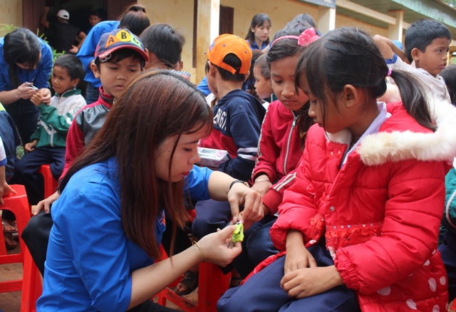 Tình nguyện viên bấm móng tay cho thiếu nhi buôn Hô, xã Ea Drong, huyện Cư M’gar. 
