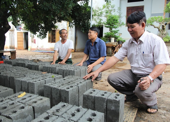 Cựu chiến binh Vũ Ngọc Nhanh (bìa trái) đang tư vấn người dân trong xã lựa chọn vật liệu xây dựng. 