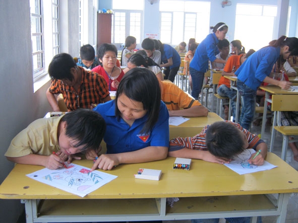 Các thành viên Hoa tình nguyện hướng dẫn các em tập vẽ trong một lần thực hiện chương trình thiện nguyện.