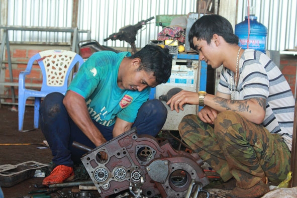 Anh Y Đen Ayun (bên trái) cùng học trò của mình sửa chữa máy nông nghiệp. 