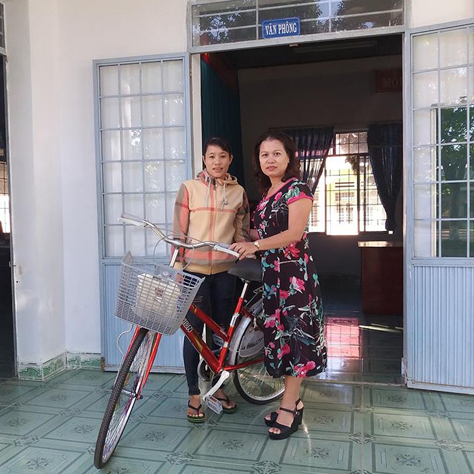 Cô Trương Thị Sâm (phải) trao xe đạp tặng học sinh nghèo. 
