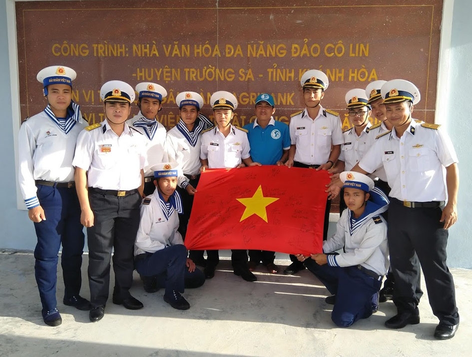 Cán bộ, chiến sĩ đảo Cô Lin đón nhận lá cờ Tổ quốc do CLB Tuổi trẻ vì biển đảo quê hương trao tặng. 
