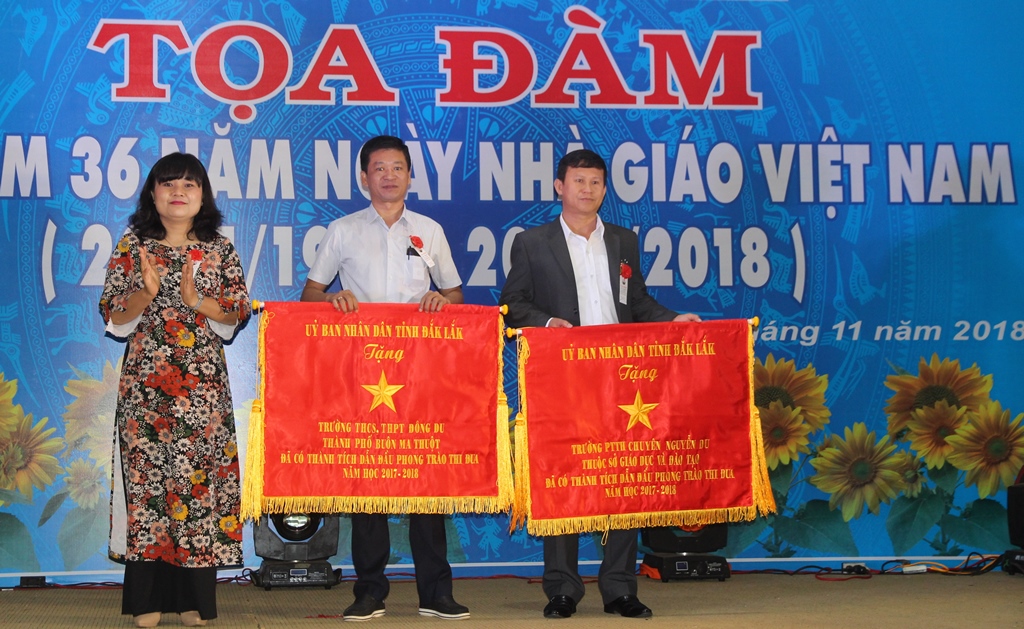 Phó Chủ tịch UBND tỉnh H’Yim Kđoh trao Cờ thi đua của UBND tỉnh tặng Trường Đông Du (đứng giữa) vì thành tích dẫn đầu phong trào thi đua năm học 2017-2018. 