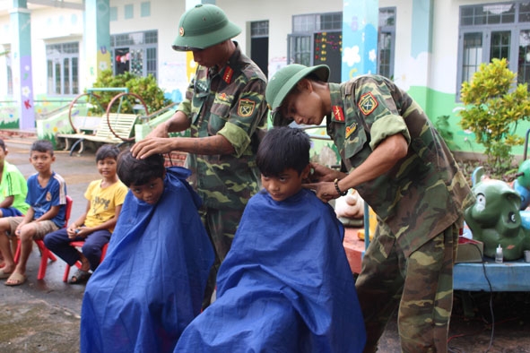 Chiến sĩ Tiểu đoàn 303 (Trung đoàn 584, Bộ CHQS tỉnh) cắt tóc cho trẻ em xã Hòa Xuân,  TP. Buôn Ma Thuột.