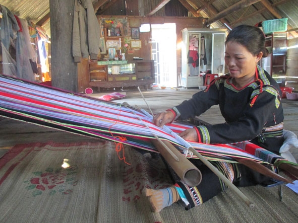 Chị Amí H'Bơi buôn Cư Phiăng (xã Hòa Phong) đang dệt một tấm đắp.  