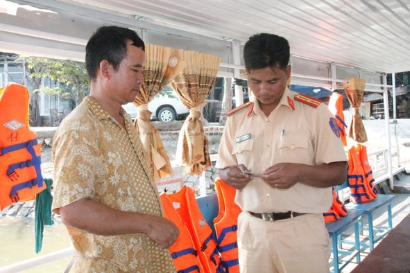 Công an huyện Lắk kiểm tra giấy chứng nhận thuyền viên của người lái thuyền. 