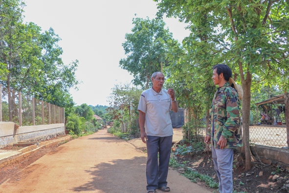 Già làng Y Găn Niê (bên trái) vận động người dân trong buôn Tung Krắk tham gia xây dựng nông thôn mới.