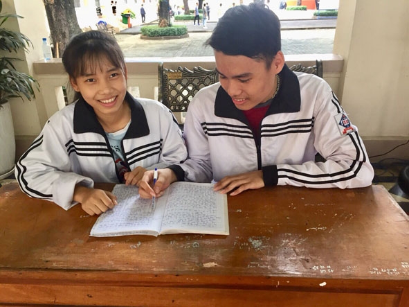 Em Quách  Văn Hòa  (bên phải)  trao đổi bài  với bạn  trong giờ  giải lao.   