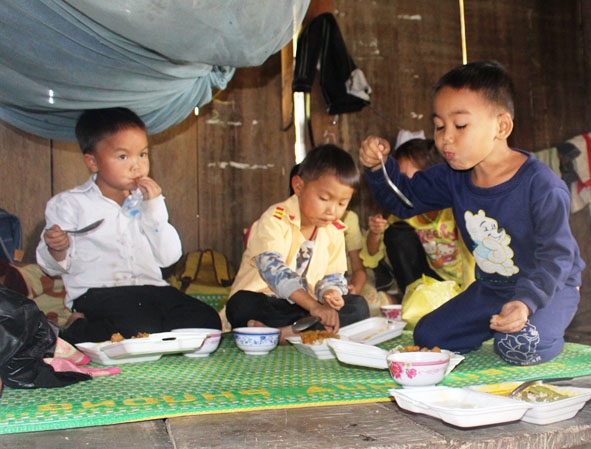 Các em nhỏ tại khu tái định cư thôn Giang Đông ăn những phần cơm có thịt được phát.