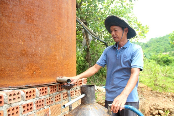 Ông Nguyễn Văn Nam chiết xuất tinh dầu sả thành phẩm ở lò chưng cất. 