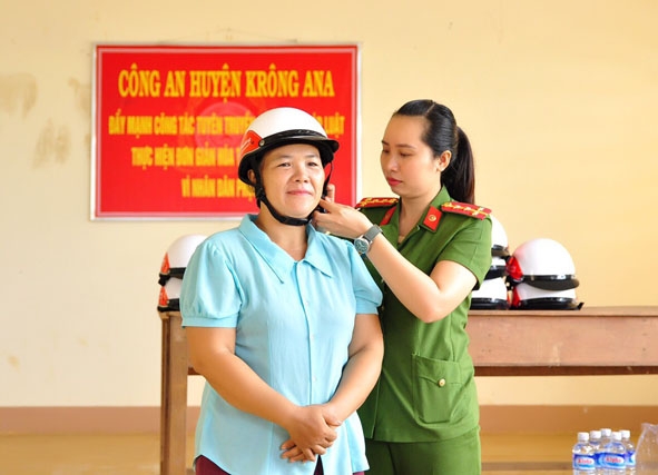 Cán bộ Công an huyện Krông Ana hướng dẫn người dân cách sử dụng mũ bảo hiểm đúng quy cách khi tham gia giao thông. 