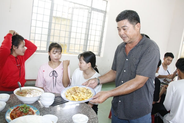 Ông Hồ Quốc Nam dọn đồ ăn cho thí sinh trọ thi tại nhà bếp khu bán trú Trường THPT Lắk.