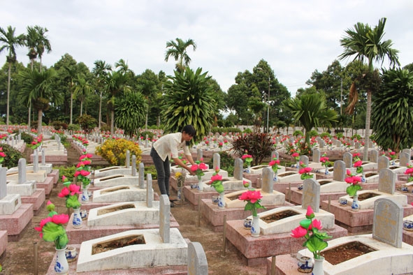 Chị Trần Thị Hoa chăm sóc các phần mộ liệt sỹ tại nghĩa trang.   