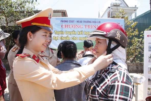 Chiến sĩ Phòng CSGT (Công an tỉnh) tặng mũ bảo hiểm cho người dân tham gia giao thông trên Quốc lộ 26  đoạn qua thị trấn Ea Knốp (huyện Ea Kar). 