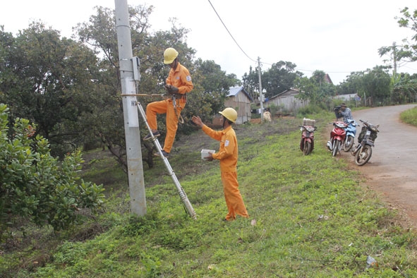 Công nhân Công ty Điện lực Đắk Lắk bảo dưỡng đường dây, công tơ điện cho  đồng bào dân tộc thiểu số buôn  Xê Đăng.  