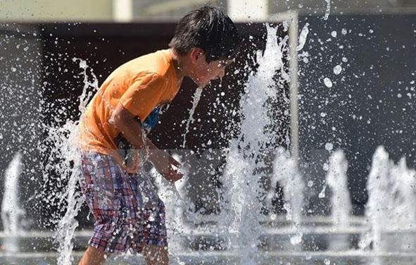 Trẻ em chơi dưới vòi nước để tránh nóng bức tại công viên thành phố Los Angeles, bang California (Mỹ). 
