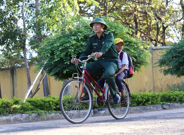 Cháu Đinh Tiến Lợi được cán bộ Đồn Biên phòng Ia R'vê chở đến trường học.