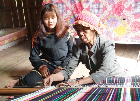 Bà H’Pêl Niê ở buôn Đắk Tuôr, xã Cư Pui (huyện Krông Bông) dạy con cháu cách dệt vải thổ cẩm truyền thống của dân tộc M'nông. 