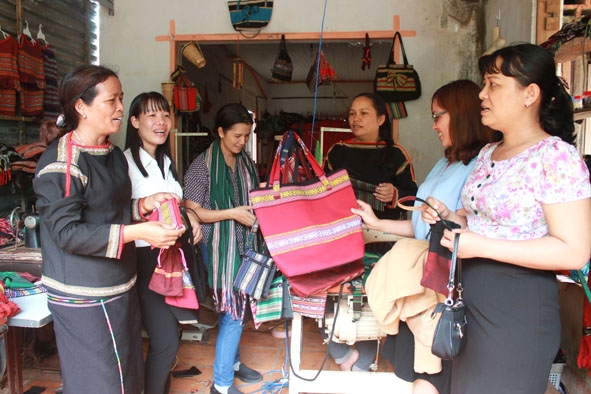 Chị H'Yam Bkrông (bìa trái), Chủ nhiệm Hợp tác xã Dệt thổ cẩm Tơng Bông (xã Ea Kao, TP. Buôn Ma Thuột) giới thiệu sản phẩm cho du khách.  