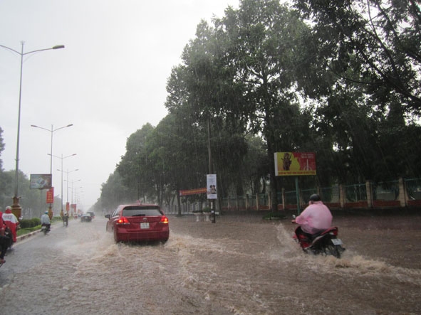 Nước ngập như suối trên đường Nguyễn Tất Thành (TP. Buôn Ma Thuột) sau cơn mưa lớn khiến người tham gia giao thông phải đi vào giữa lòng đường. Ảnh: Trương Nhất Vương