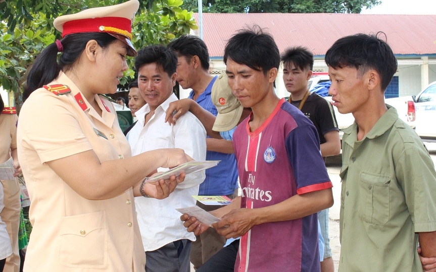 Cán bộ Phòng Cảnh sát gia thông phát tờ rơi và hướng dẫn về Luật an toàn giao thông cho người dân xã Cư San (huyện M'Đrắk). 