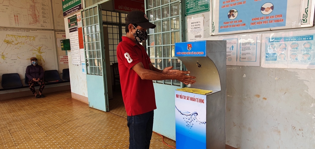 Người dân  sử dụng  máy rửa tay sát khuẩn  tự động  khi đến  liên hệ  công việc tại trụ sở UBND xã Ea M'nang.