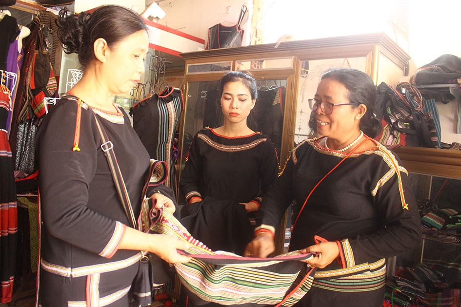 Bà H'Yam Bkrông, Giám đốc HTX Dệt thổ cẩm Tơng Bông (bìa phải) giới thiệu các sản phẩm của hợp tác xã. 