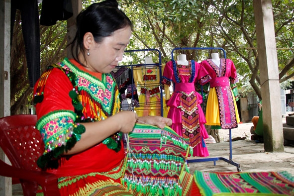 Chị Sùng Thị Tỉnh (thôn 11, xã Cư San) đính cườm cho sản phẩm vòng quấn chân.