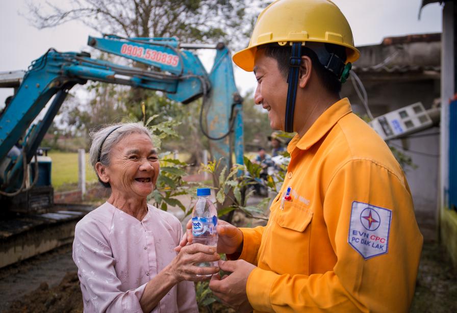 Người dân mang nước uống ra tận công trình mời công nhân PC Đắk Lắk  khi đến khôi phục lưới điện