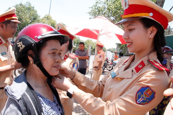 Cán bộ Phòng CSGT Công an tỉnh tặng mũ bảo hiểm cho người dân.
