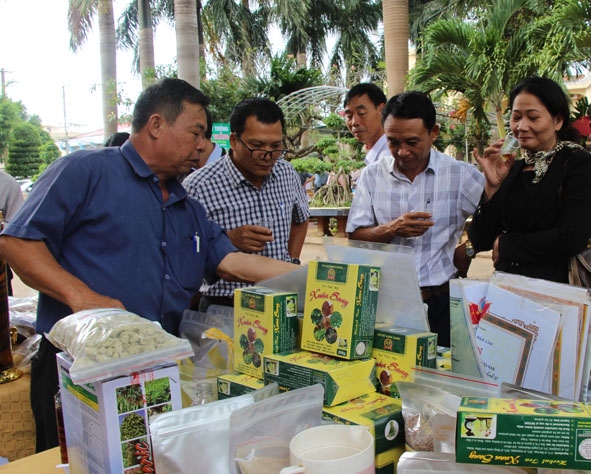 Giám đốc Hợp tác xã Nông nghiệp, dịch vụ Hợp Nhất (xã Ea Ô, huyện Ea Kar) Phan Đình Xuân (bìa trái)  giới thiệu sản phẩm của đơn vị.   