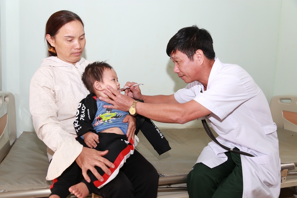 Bác sĩ  Nguyễn  Quang Cúc  thăm khám  cho một  bệnh nhi.   