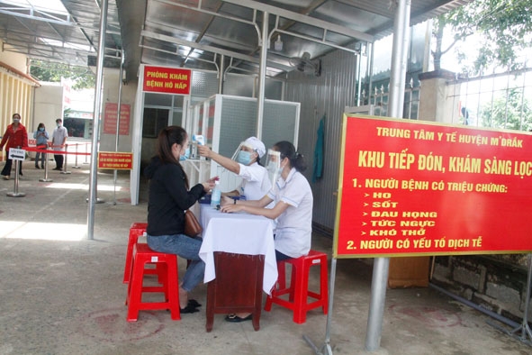 Cán bộ Trung tâm Y tế huyện M'Drắk kiểm tra thân nhiệt người dân đến thăm khám.