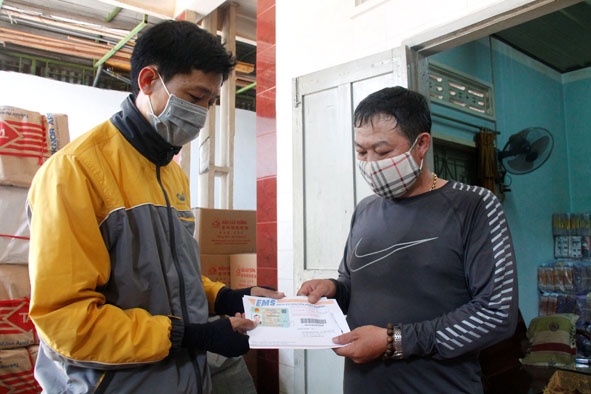 Bưu tá Lê Minh Thắng (bên trái) giao thẻ căn cước công dân cho khách hàng tại phường Tân Thành,  TP. Buôn Ma Thuột.