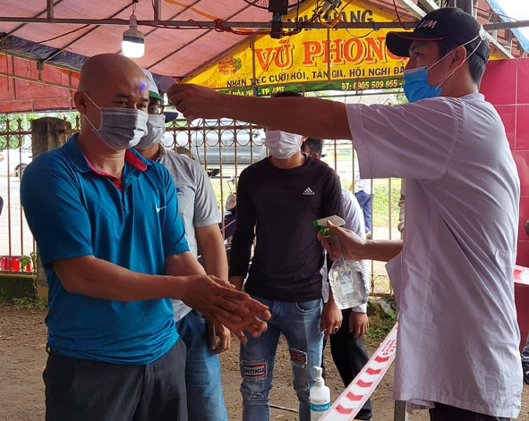 Cán bộ y tế đo thân nhiệt trước khi người dân vào khai báo y tế tại chốt kiểm soát phòng, chống dịch trên Quốc lộ 14 đoạn qua xã Hòa Phú (TP. Buôn Ma Thuột).
