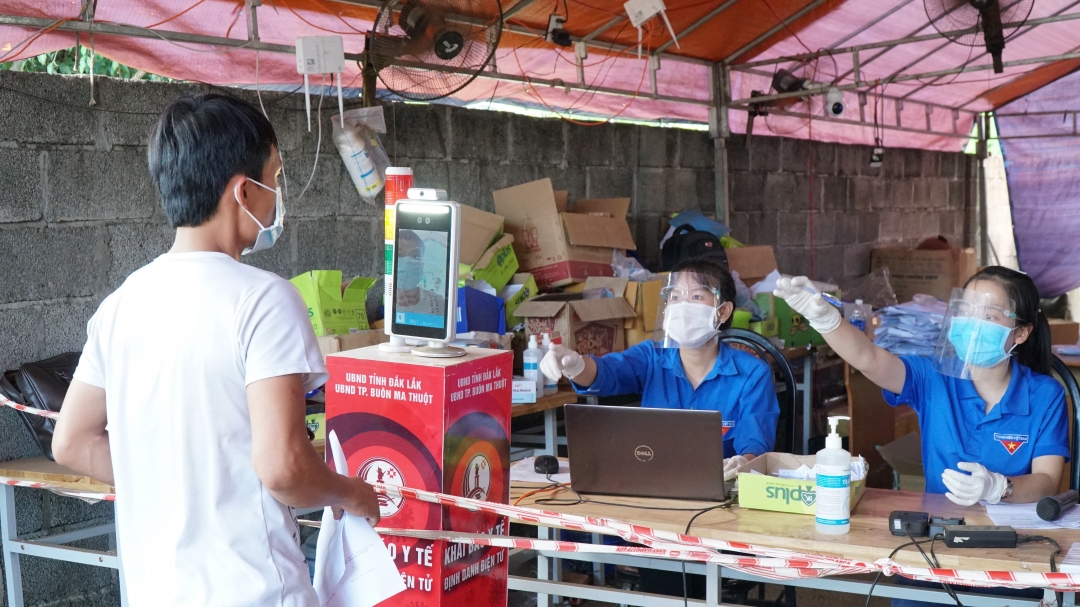 Người dân đứng vào máy nhận diện khuôn mặt để hoàn tất việc khai báo y tế điện tử tại Chốt kiểm soát phòng, chống dịch COVID-19 trên Quốc lộ 14,  đoạn qua xã Hòa Phú (TP. Buôn Ma Thuột).